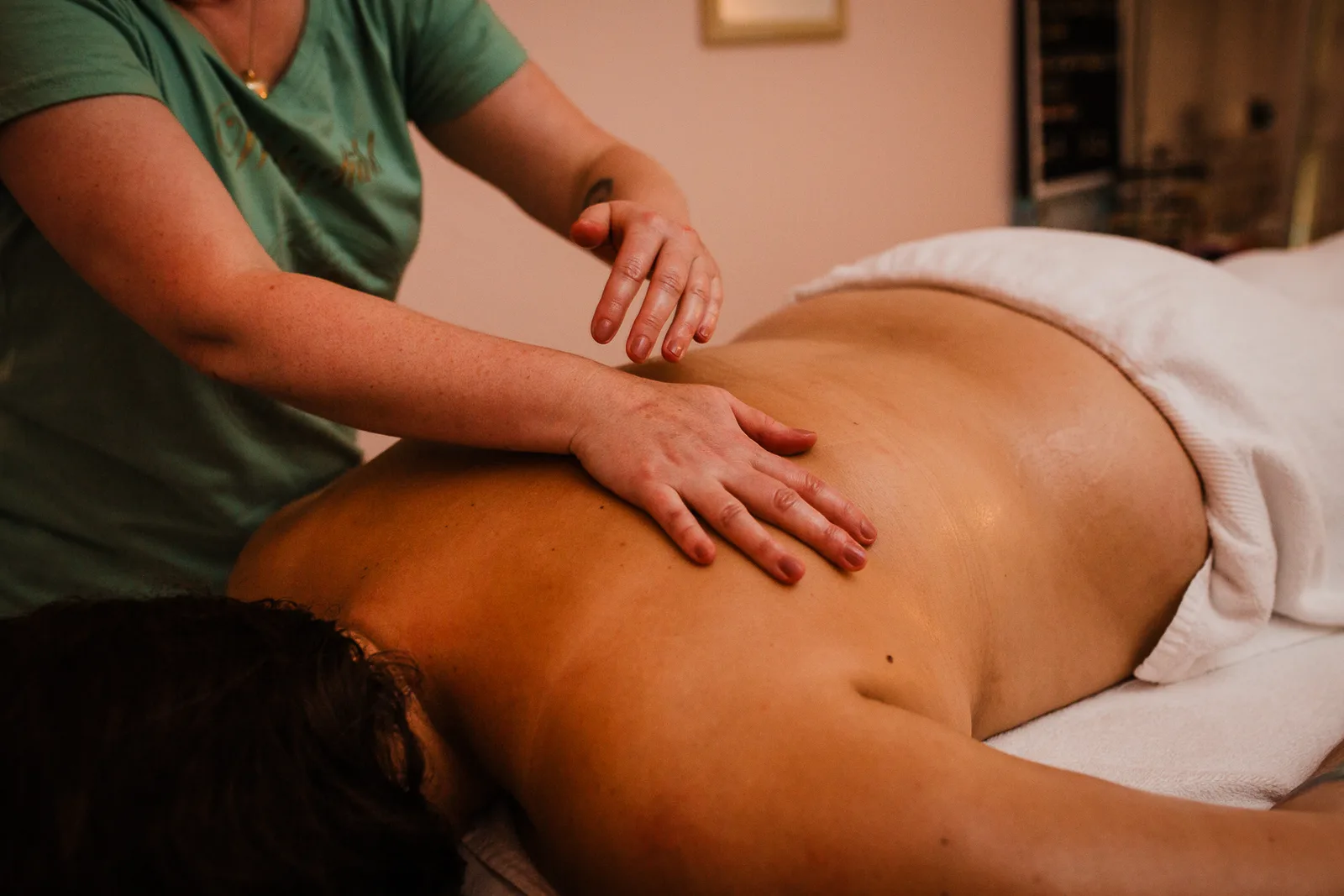 Sanfte Wellnessmassage im warm beleuchteten Behandlungsraum